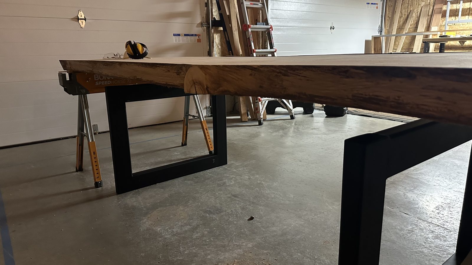 A ten-foot live-edge slab resting on welded black steel box-frame legs